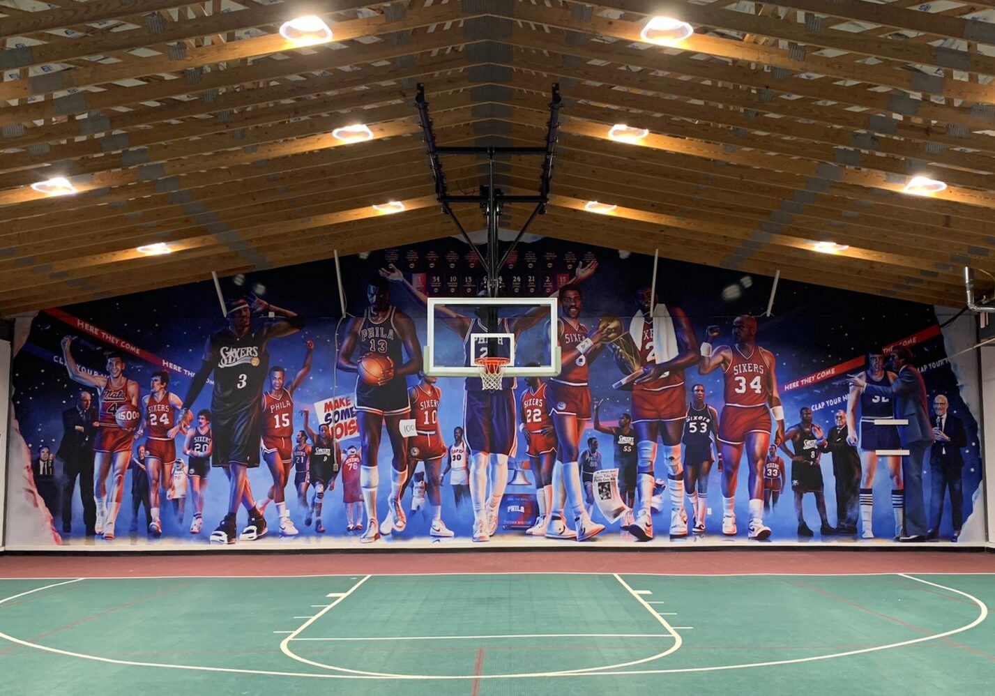 Indoor basketball court with mural of players dunking.