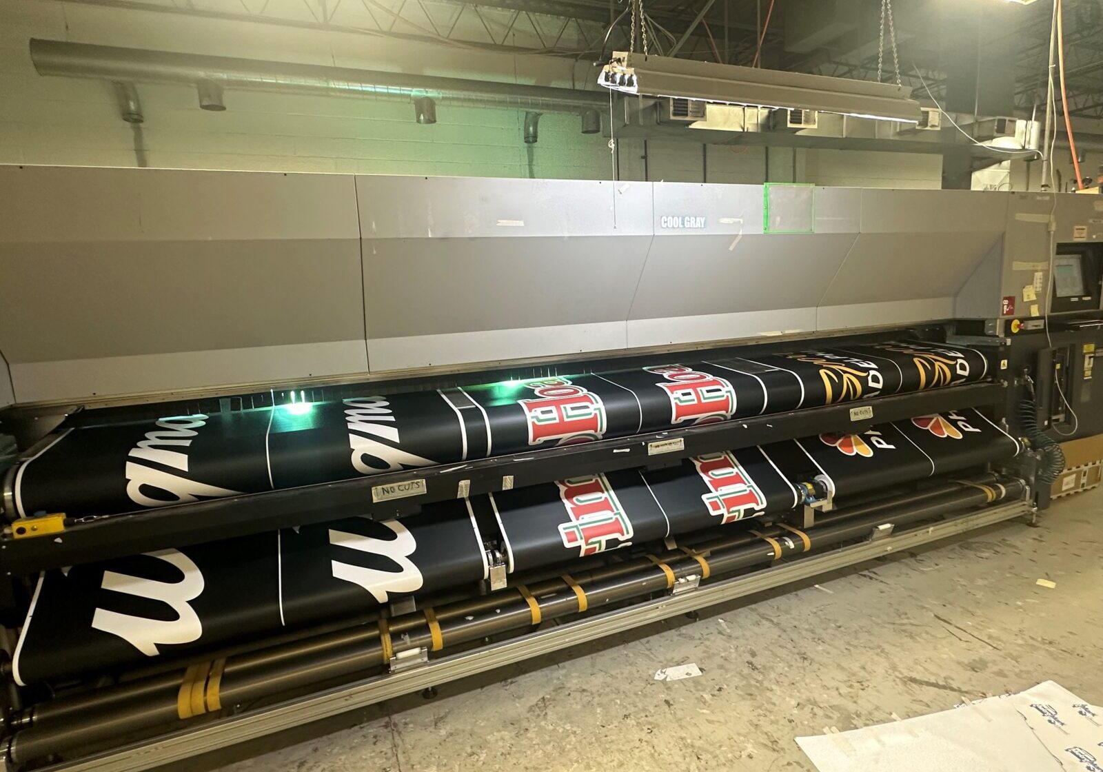 Industrial printer producing large black banners with white and red text.